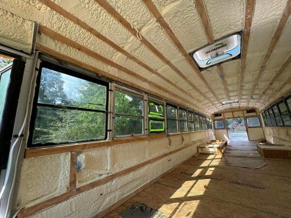 Interior of insulated school bus conversion with closed-cell spray foam on roof and window framing, Conroe, TX