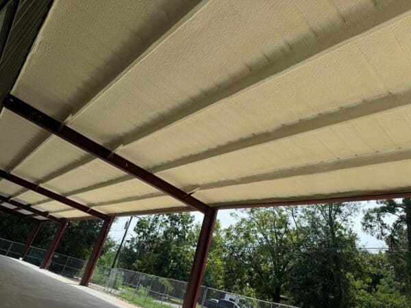 Closed-cell spray foam insulation on the underside of a covered steel structure roof, Humble, TX commercial project